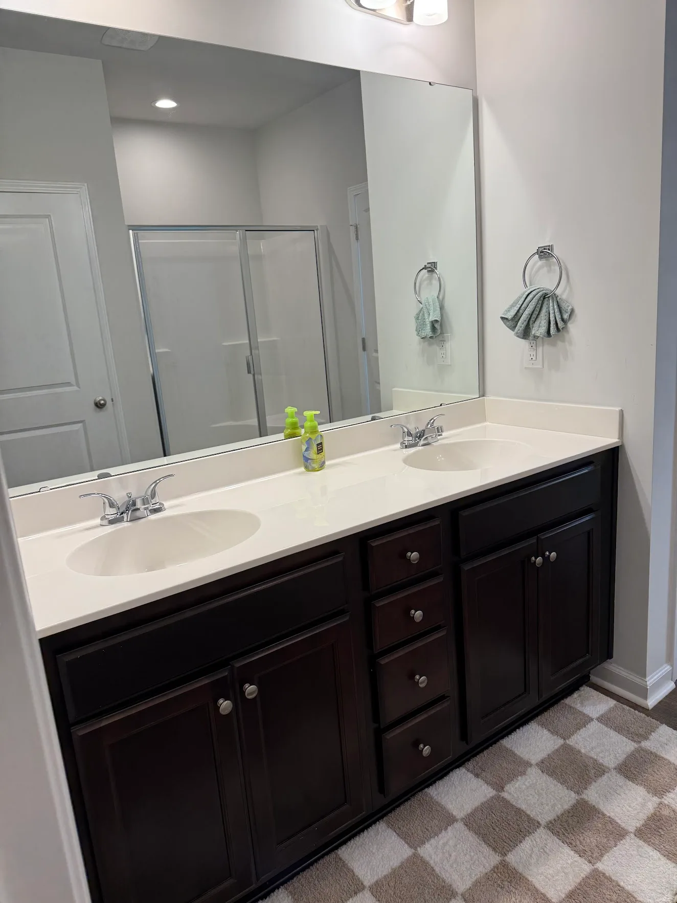 A clean bathroom vanity with two white sinks, dark wood cabinets and a large mirror