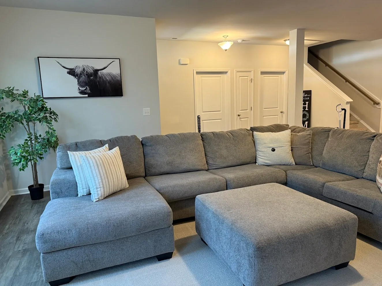 A neat living room with a grey sectional sofa and ottoman